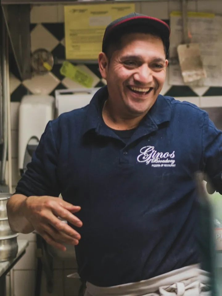Dono de pizzaria rindo na cozinha do próprio negócio (foto ilustrativa)