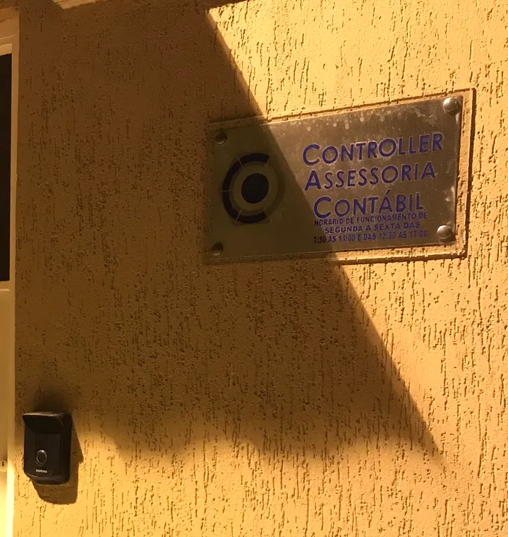 Placa da Controller Assessoria Contábil na parede, ao lado do portão do escritório