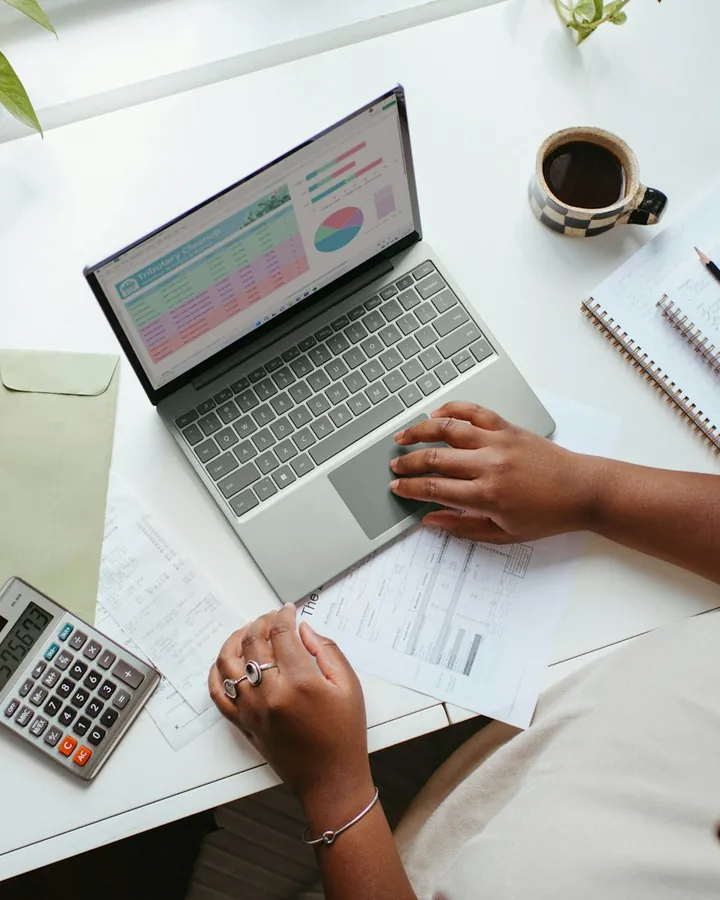 Mesa de trabalho com notebook, calculadora e documentos (foto ilustrativa)